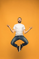 Image showing Freedom in moving. handsome young man jumping against orange background