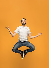 Image showing Freedom in moving. handsome young man jumping against orange background