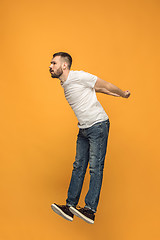 Image showing Freedom in moving. handsome young man jumping against orange background