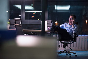 Image showing businessman using mobile phone in dark office