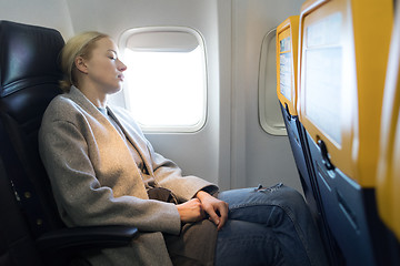 Image showing Woman napping on seat while traveling by airplane.