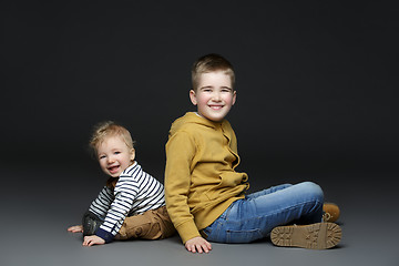 Image showing Two brothers in jeans sitting on floor