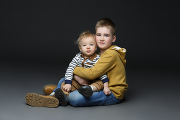 Image showing Two brothers in jeans sitting on floor