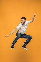 Image showing Freedom in moving. handsome young man jumping against orange background