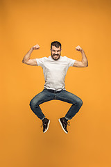 Image showing Freedom in moving. handsome young man jumping against orange background