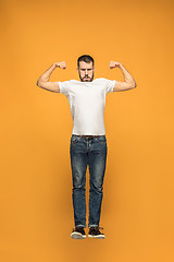 Image showing Freedom in moving. handsome young man jumping against orange background