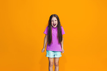 Image showing The happy teen girl standing and smiling against orange background.