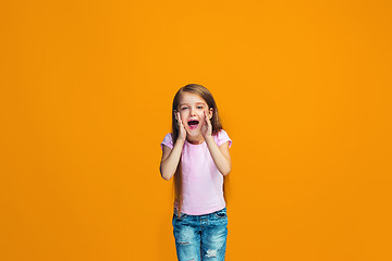 Image showing Isolated on orange young casual teen girl shouting at studio