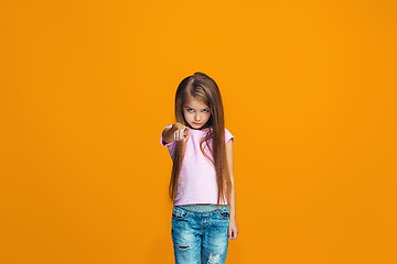 Image showing The happy teen girl pointing to you, half length closeup portrait on orange background.