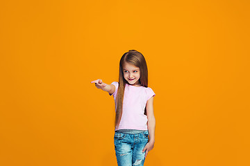 Image showing The happy teen girl pointing to you, half length closeup portrait on orange background.