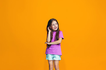 Image showing The happy teen girl standing and smiling against orange background.
