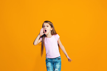 Image showing Isolated on orange young casual teen girl shouting at studio