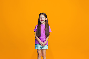 Image showing The happy teen girl standing and smiling against orange background.