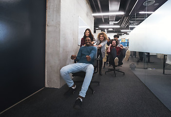 Image showing multiethnics business team racing on office chairs