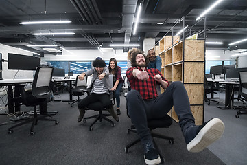 Image showing multiethnics business team racing on office chairs