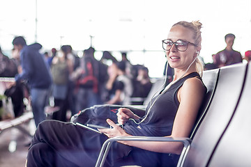 Image showing Female traveler using her cell phone while waiting to board a plane at departure gates at asian airport terminal.