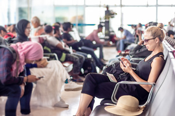 Image showing Female traveler using her cell phone while waiting to board a plane at departure gates at asian airport terminal.