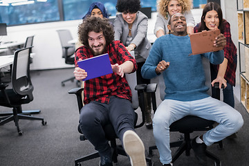 Image showing multiethnics business team racing on office chairs