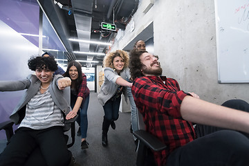 Image showing multiethnics business team racing on office chairs