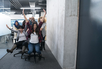 Image showing multiethnics business team racing on office chairs