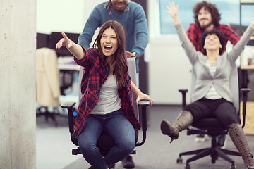 Image showing multiethnics business team racing on office chairs