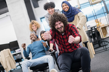 Image showing multiethnics business team racing on office chairs