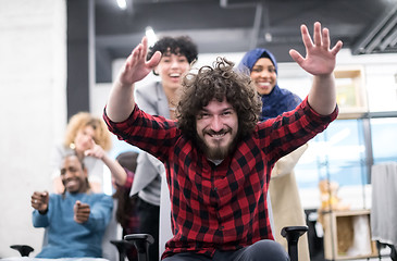 Image showing multiethnics business team racing on office chairs