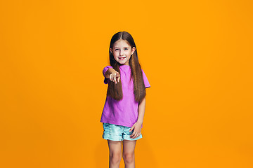 Image showing The happy teen girl pointing to you, half length closeup portrait on orange background.