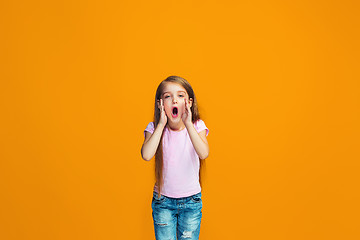 Image showing Isolated on orange young casual teen girl shouting at studio