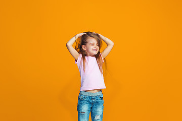 Image showing The happy teen girl standing and smiling against orange background.