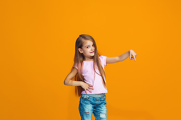 Image showing The happy teen girl presenting something, half length closeup portrait on orange background.