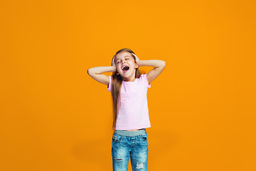 Image showing The happy teen girl standing and smiling against orange background.