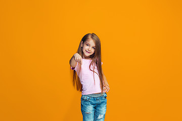 Image showing The happy teen girl pointing to you, half length closeup portrait on orange background.