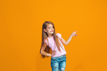 Image showing The happy teen girl presenting something, half length closeup portrait on orange background.