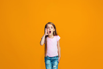 Image showing Isolated on orange young casual teen girl shouting at studio