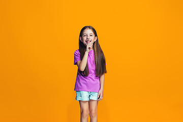 Image showing The happy teen girl standing and smiling against orange background.