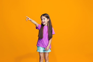 Image showing The happy teen girl pointing to you, half length closeup portrait on orange background.