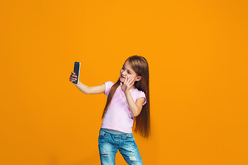 Image showing The happy teen girl standing and smiling with phone