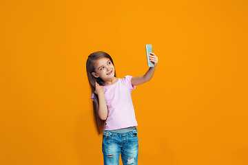 Image showing The happy teen girl standing and smiling with phone