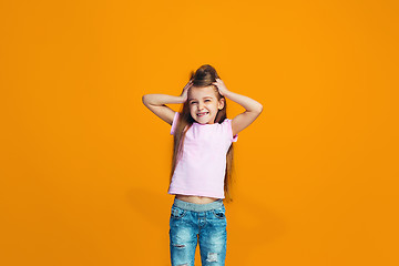 Image showing The happy teen girl standing and smiling against orange background.