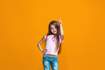 Image showing The happy teen girl presenting something, half length closeup portrait on orange background.