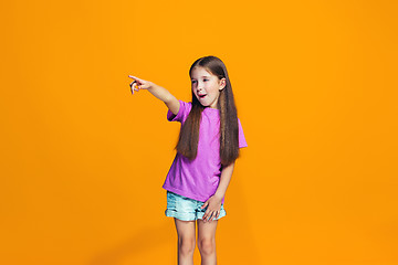 Image showing The happy teen girl pointing to you, half length closeup portrait on orange background.