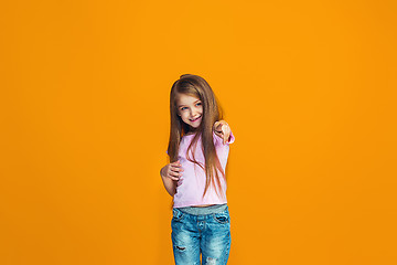 Image showing The happy teen girl pointing to you, half length closeup portrait on orange background.