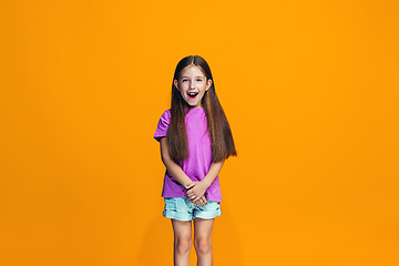 Image showing The happy teen girl standing and smiling against orange background.