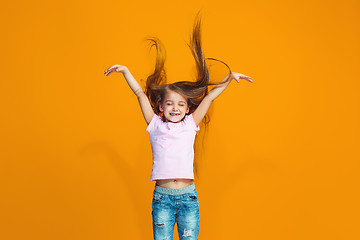 Image showing The happy teen girl standing and smiling against orange background.