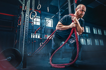 Image showing Men with battle rope battle ropes exercise in the fitness gym. CrossFit.