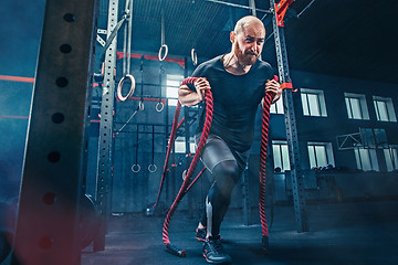 Image showing Men with battle rope battle ropes exercise in the fitness gym. CrossFit.