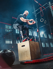 Image showing Man jumping during exercises in the fitness gym. CrossFit.