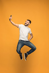 Image showing Time to take selfie. Full length of handsome young man taking selfie while jumping