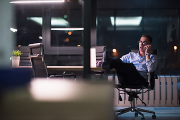 Image showing businessman using mobile phone in dark office